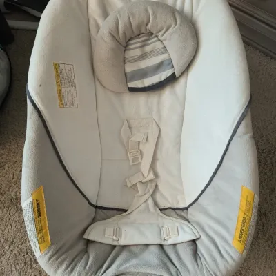 Graco infant bouncer seat with soothing vibration feature, featuring a plush cream and grey fabric cover, safety harness, and removable...