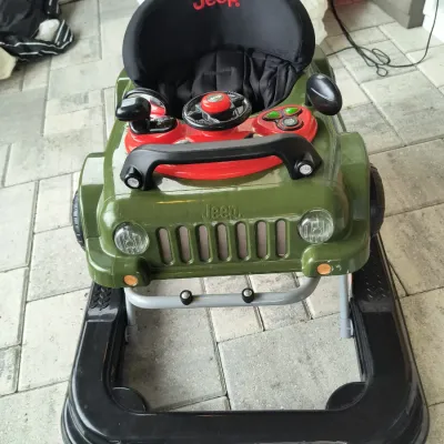 Jeep-branded baby walker in olive green and black, featuring a steering wheel and dashboard activity center.