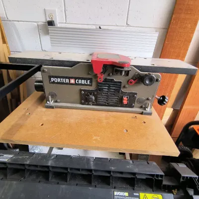 Porter-Cable benchtop jointer mounted on a wooden work surface, showing some dust and wear from use.