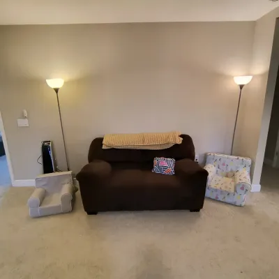 Dark brown upholstered loveseat flanked by two modern metal torchiere floor lamps and two children's armchairs.