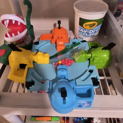Vintage Hungry Hungry Hippos board game with red marbles in a plastic bag, displayed alongside a tub of Crayola Air-Dry Clay and other...