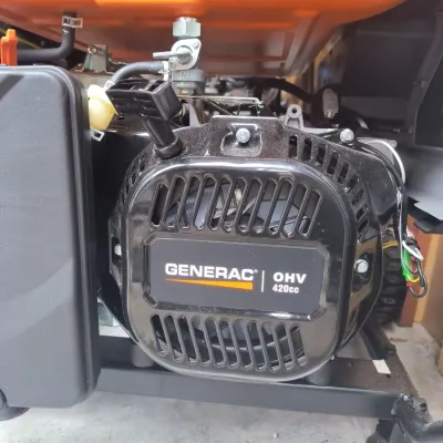 Close-up of a Generac OHV 420cc engine on a portable generator, showing the pull-start mechanism and fuel line connections.
