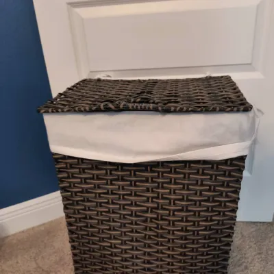 Dark brown woven wicker laundry hamper with a hinged lid and a removable white fabric liner.