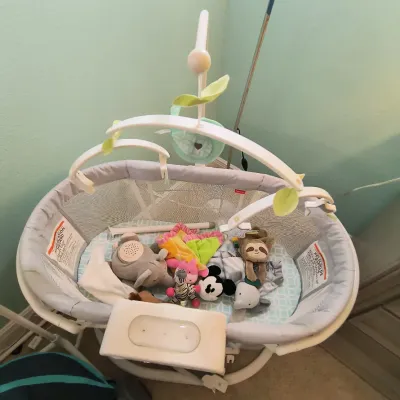 Fisher-Price Soothing Motions Bassinet with mesh sides, overhead mobile, and an assortment of plush baby toys.