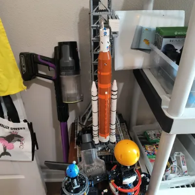 Assembled LEGO Technic Planet Earth and Moon in Orbit set and LEGO Icons NASA Artemis Space Launch System set, displayed on a wooden...