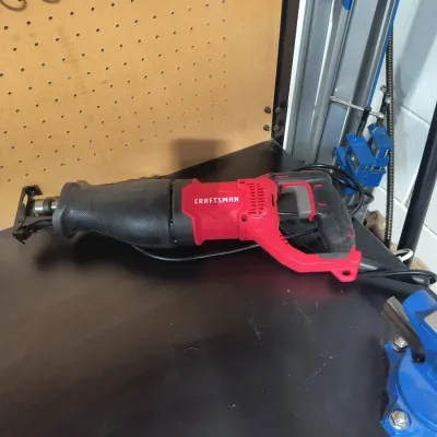 Craftsman corded reciprocating saw in red and black, resting on a workbench.