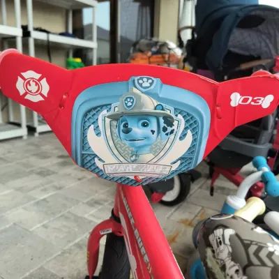 Paw Patrol Marshall themed children's bicycle, featuring a red frame and a handlebar shield with Marshall the dalmatian character...