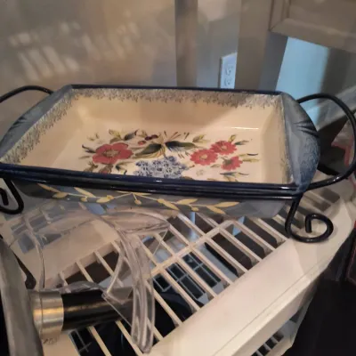 Temp-tations floral ceramic baking dish with a blue rim and matching black metal wire serving rack.