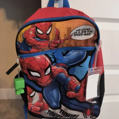 Spider-Man themed child's backpack in red, blue, and black, featuring comic-style graphics, a clear luggage tag, and a green...