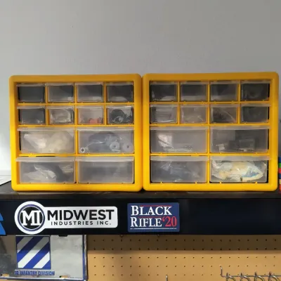 Two yellow plastic multi-drawer storage organizers filled with various small hardware and parts, sitting on a shelf above a pegboard.