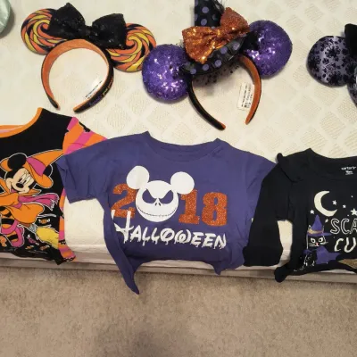Collection of Disney Halloween items, including Minnie Mouse ear headbands and children's graphic t-shirts.