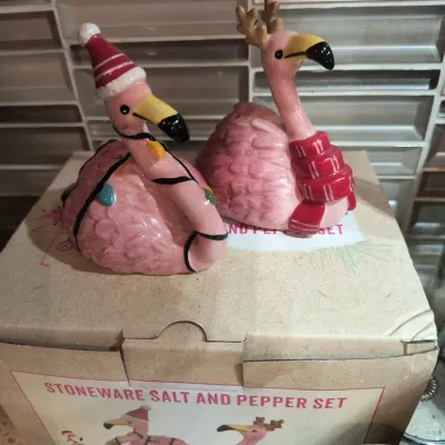 Whimsical stoneware salt and pepper shaker set featuring pink flamingos dressed in holiday attire, complete with original packaging.