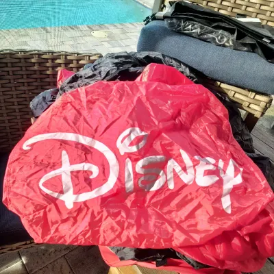 Red and black Disney-branded nylon bag or cover, shown outdoors on patio furniture.