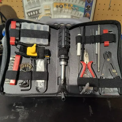 Precision electronics repair tool kit in a zippered black carrying case, featuring a ratcheting screwdriver, pliers, wire strippers, and...