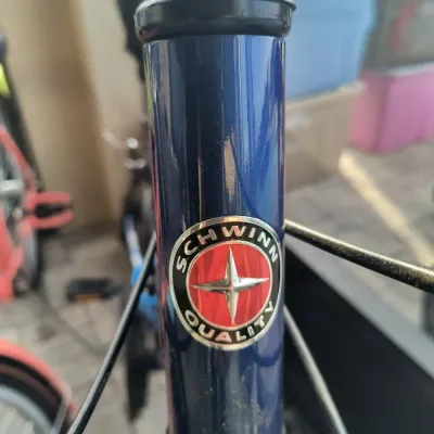 Schwinn Quality head tube badge on a blue bicycle frame, showing the classic four-point star logo.