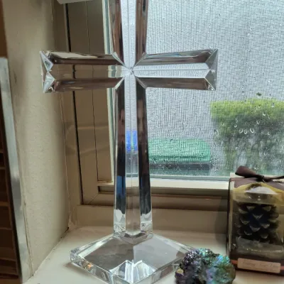 Waterford crystal standing cross with a faceted design, displayed on a windowsill alongside a small iridescent mineral specimen.