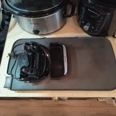 Presto electric griddle with detachable handles and power cord, shown alongside a stainless steel Crock-Pot and an Instant Pot multi-cooker.