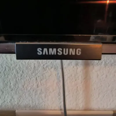 Close-up of a Samsung television bezel and stand, showing the logo and lower control buttons.