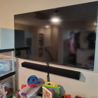 Wall-mounted Vizio flat-screen television with a matching black soundbar, positioned above a shelf of children's toys.