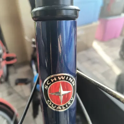 Schwinn Quality head badge on a dark blue bicycle frame, showing some light wear.