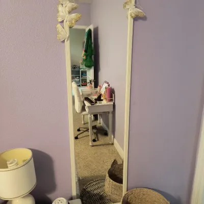Full-length wall mirror with a white frame, decorated with gold-accented butterfly ornaments on the upper corners.