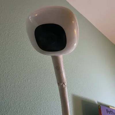 Nanit smart baby monitor camera mounted on a floor stand, designed for overhead crib viewing.