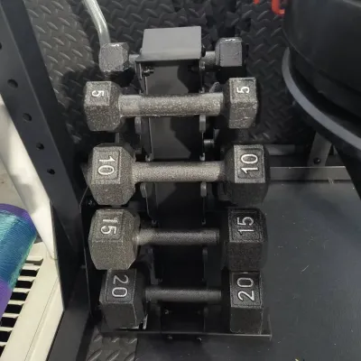 Set of cast iron hexagonal dumbbells ranging from 5 to 20 pounds, stored on a vertical black metal A-frame rack.