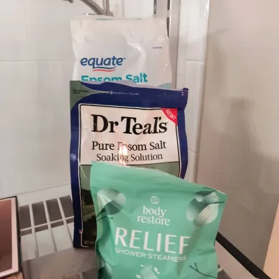 Assorted bath products including Equate Epsom Salt, Dr Teal's Pure Epsom Salt Soaking Solution, and Body Restore Relief Shower...