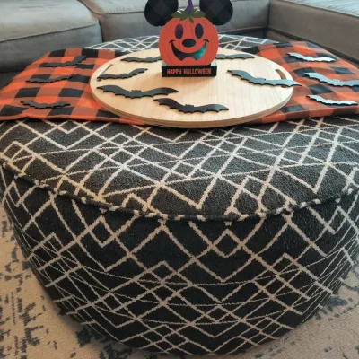 Large round upholstered ottoman with a black and white geometric pattern, styled with a wooden tray and Halloween decorations.