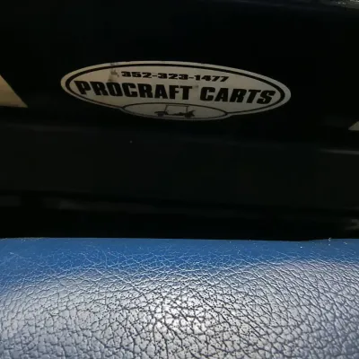 Procraft Carts dealer decal on a golf cart body, positioned above a blue textured vinyl seat.