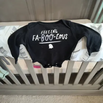 Black long-sleeve baby bodysuit featuring a Halloween-themed "Feeling Fa-Boo-Lous" graphic with a small ghost illustration.