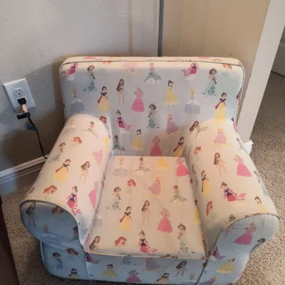 Child-sized upholstered armchair featuring a Disney Princess pattern on a light blue background.