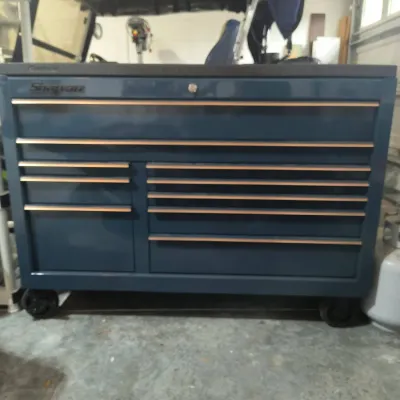 Snap-on rolling tool chest in dark blue with copper-toned drawer pulls, featuring multiple drawers and a locking mechanism.