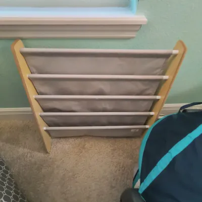 Children's sling bookshelf featuring a light wood frame and five grey fabric storage pockets.