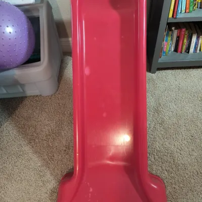 Little Tikes red plastic toddler slide, showing some light scuffs and wear from use.
