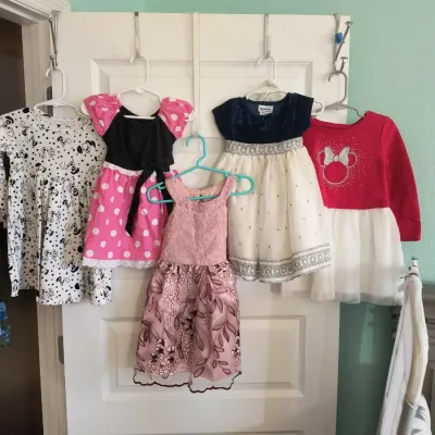 Assortment of toddler and girls' dresses, including Disney-themed Minnie Mouse and 101 Dalmatians styles, alongside formal party...
