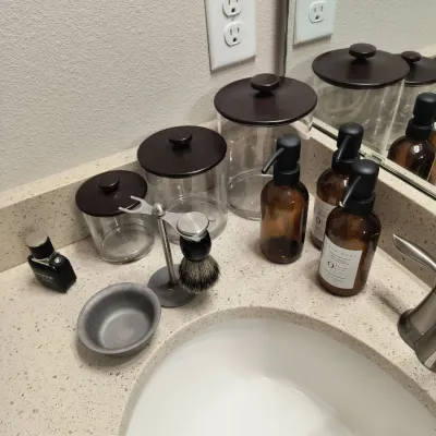 Assorted bathroom vanity accessories, including three glass canisters with dark brown lids, three amber glass soap dispensers, and a...