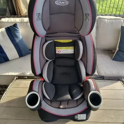 Graco 4Ever 4-in-1 convertible car seat in black, gray, and pink, featuring built-in cup holders and side-impact protection.