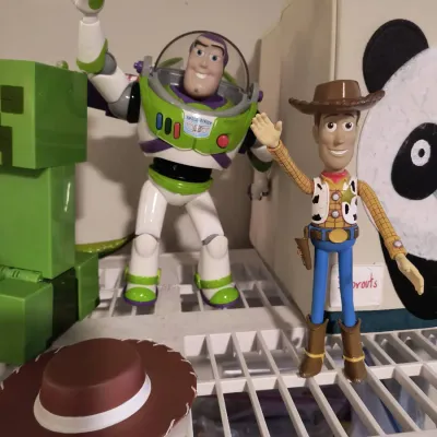 Toy Story action figures featuring Buzz Lightyear and Woody, displayed alongside a Minecraft Creeper figure and a small cowboy hat...