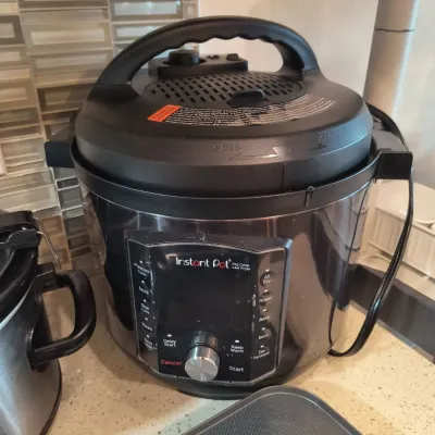 Instant Pot Pro Crisp multi-cooker and air fryer in black and stainless steel finish, showing light use.