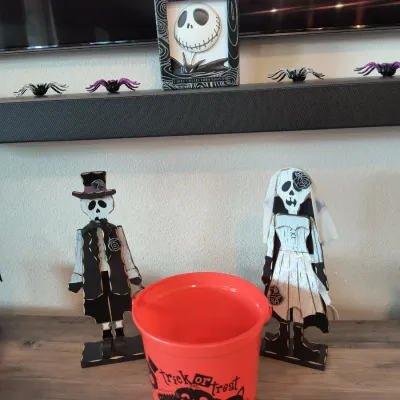 Collection of Halloween decorations, including a pair of wooden skeleton bride and groom figures, an orange plastic trick-or-treat...