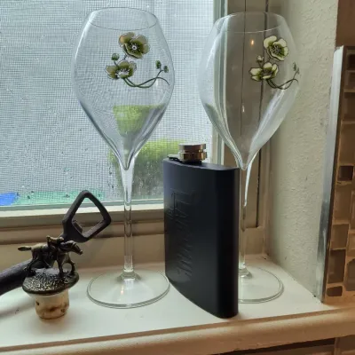 Pair of Perrier-Jouët Belle Epoque champagne flutes featuring the signature anemone design, displayed alongside a black Larceny Bourbon...