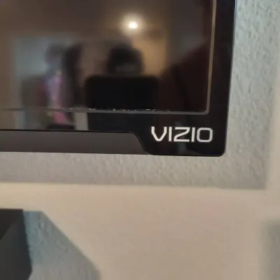 Close-up of a Vizio flat-screen television showing the brand logo on the bottom right corner of the black bezel.