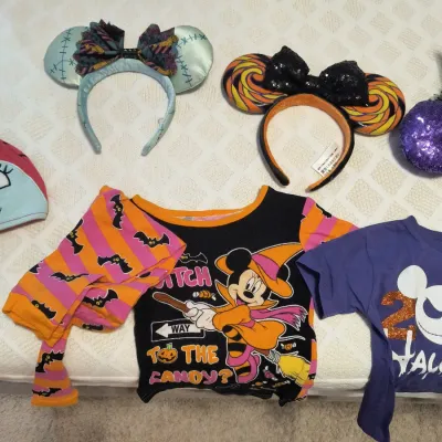 Collection of Disney Halloween-themed apparel and accessories, including Minnie Mouse ear headbands and children's graphic t-shirts.