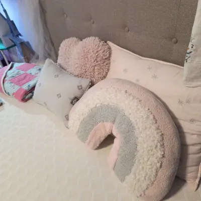 Assortment of children's decorative pillows, including a plush rainbow-shaped pillow, a pink heart-shaped shag pillow, and an UGG...