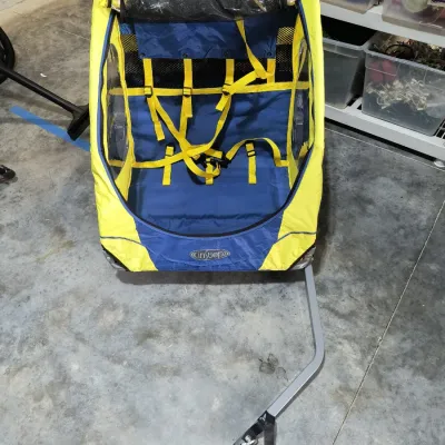 InStep double child bicycle trailer in yellow and blue, featuring a five-point safety harness and a roll-up mesh screen.
