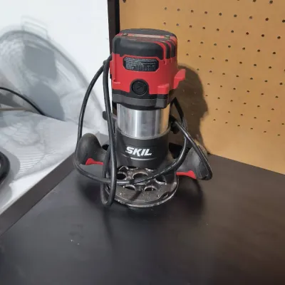 Skil corded plunge router with a red and black motor housing, showing light signs of use.
