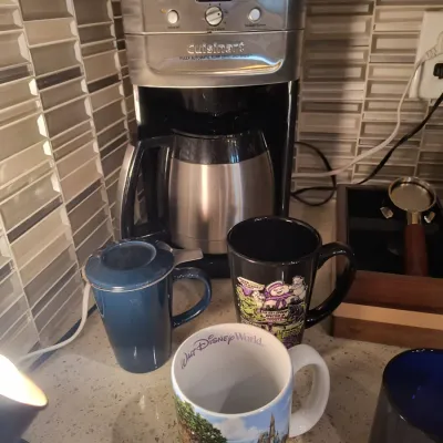 Cuisinart fully automatic burr grind and brew coffee maker with thermal carafe, shown alongside a selection of novelty mugs including a...
