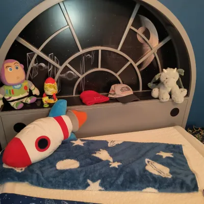 Star Wars themed twin bed frame featuring a Millennium Falcon cockpit-style headboard with built-in shelf, shown with space-themed...