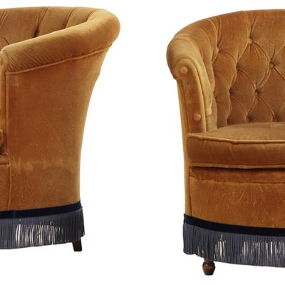 A PAIR OF FRENCH UPHOLSTERED TUB CHAIRS HAVING BUTTON BACK UPHOLSTERY AND FRINGE DECORATION CIRCA